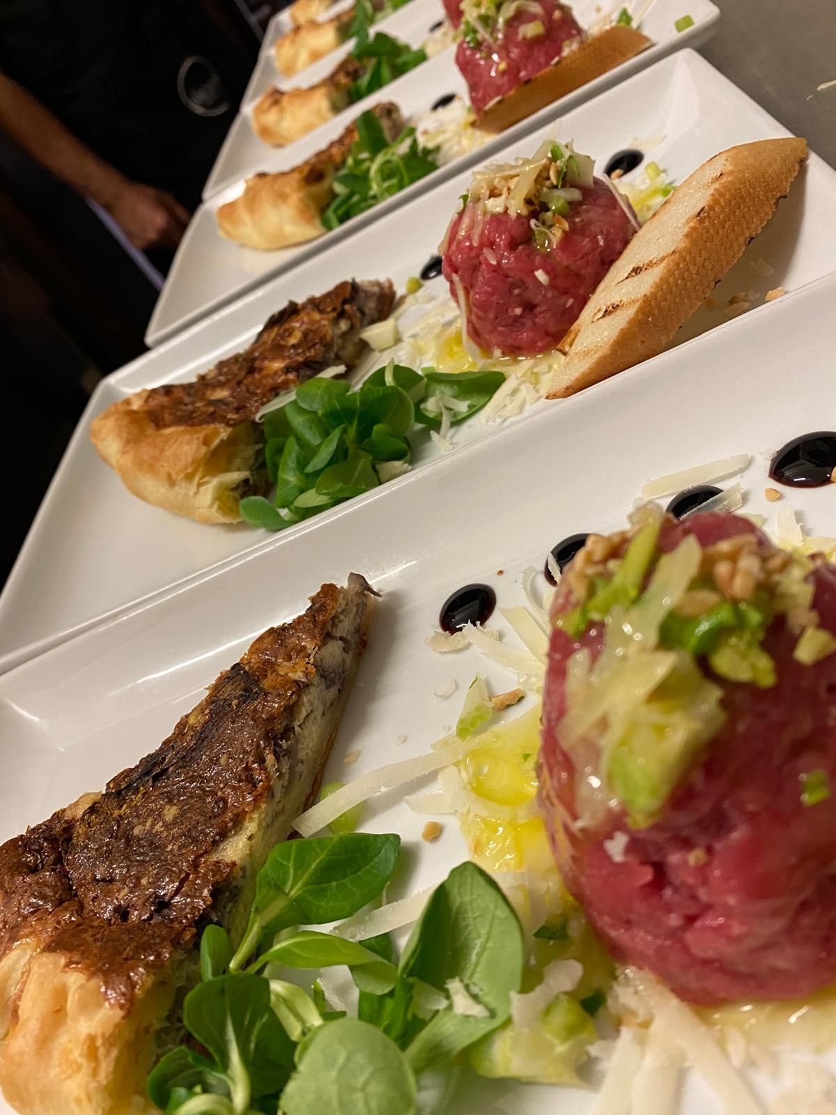 Cibo servito: tartare di manzo con pane tostato, guarnito con verdure e noci tritate.