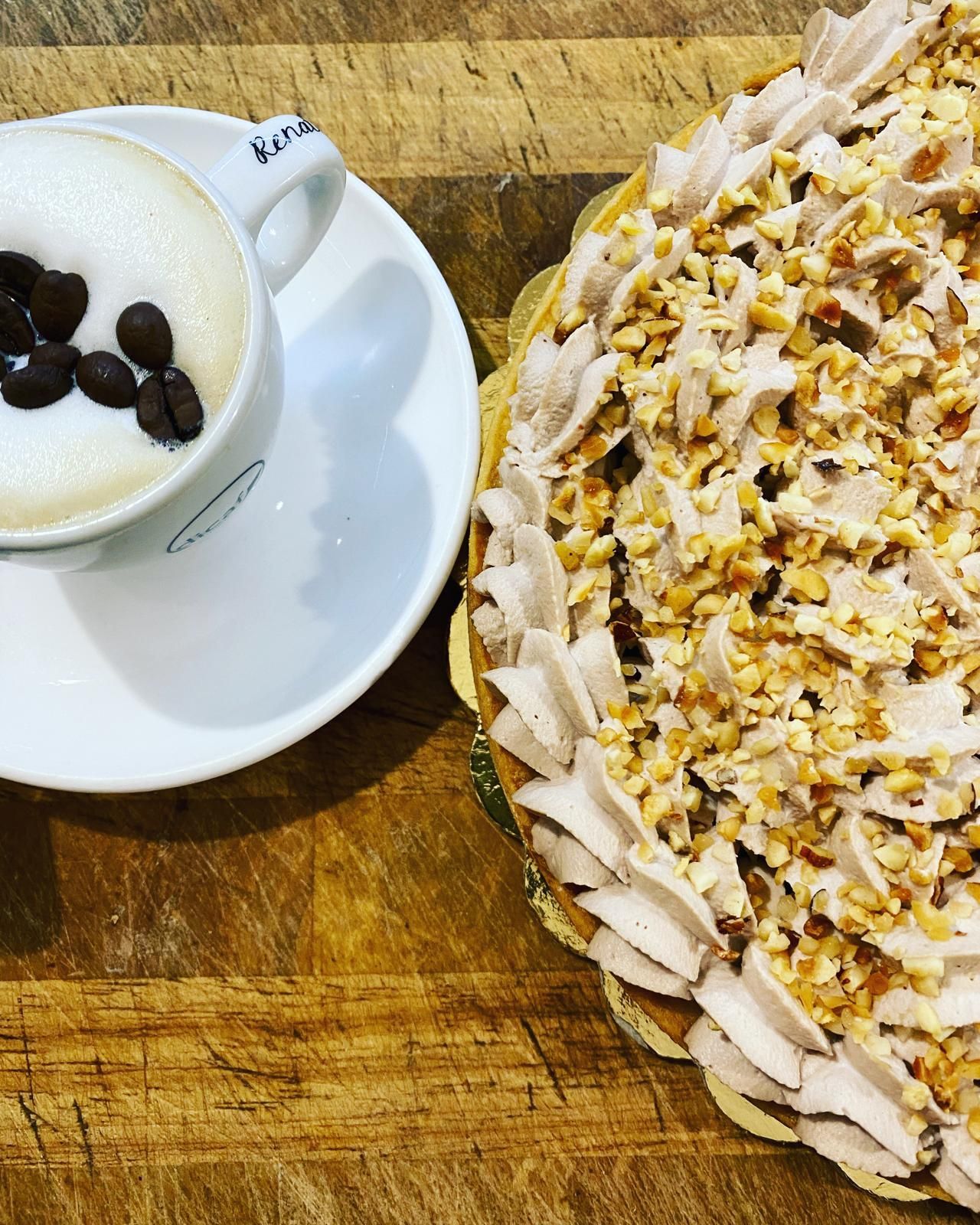 Cappuccino e torta ricoperta di noci su una superficie di legno.