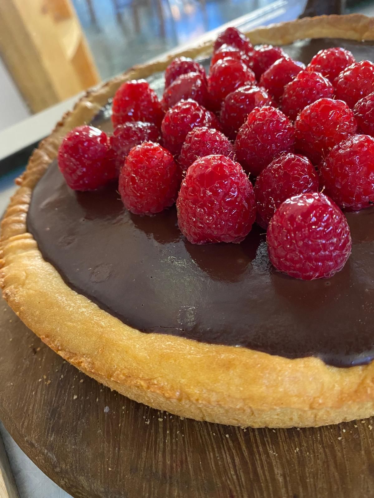 Crostata al cioccolato con lamponi su una superficie di legno.