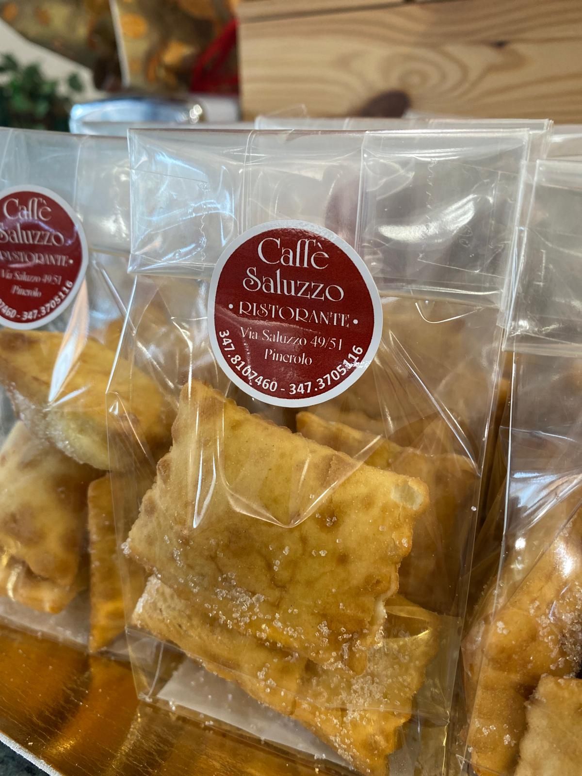Sacchetti di paste fritte con l'adesivo rosso e bianco del Caffè Saluzzo, probabilmente in vendita in un negozio.