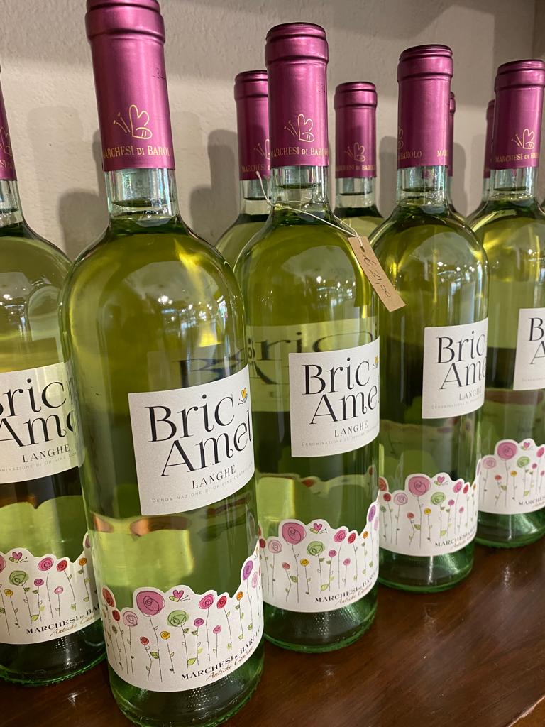 Bottiglie di vino bianco Bric Amè con tappi rosa e gonne di carta floreali.