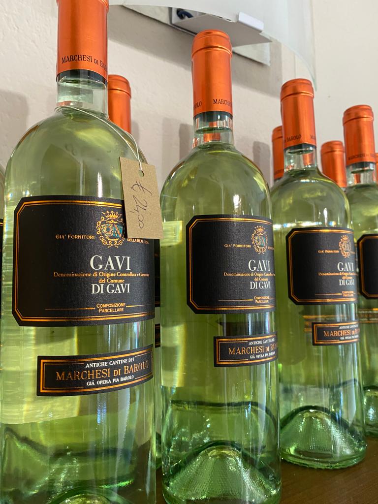 Bottiglie di vino Gavi di Gavi con tappi arancioni ed etichette nere, disposte in fila.