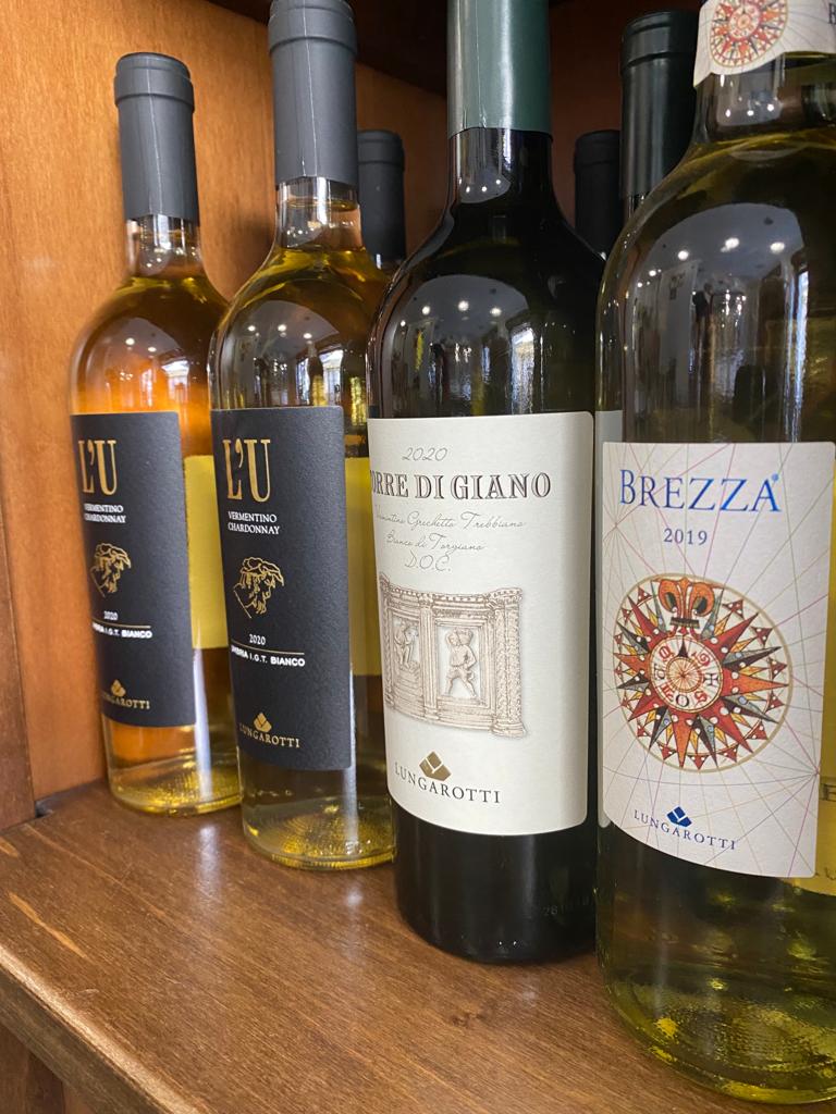 Bottiglie di vino su uno scaffale di legno, etichette diverse, tonalità di giallo e verde.