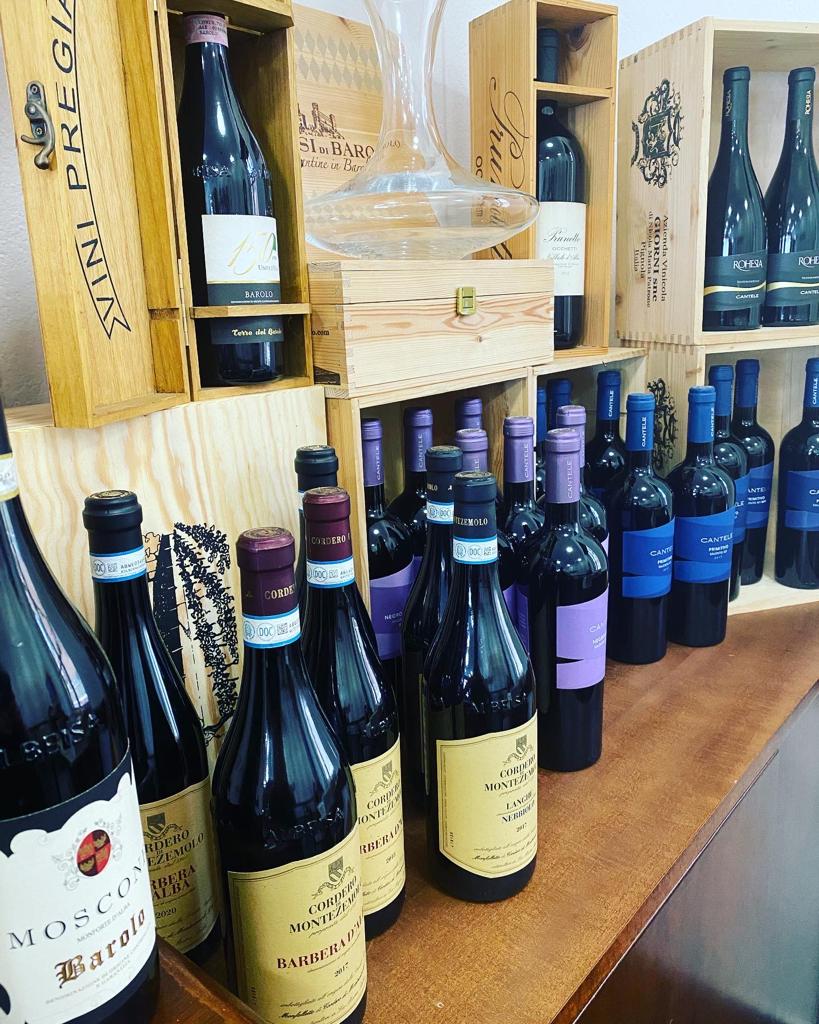 Bottiglie di vino esposte su scaffali e casse di legno.