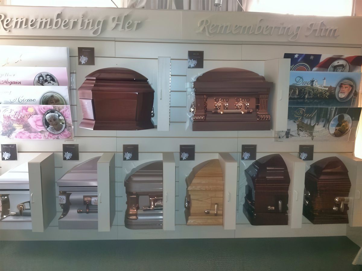 Display of various coffins at a funeral home. Some are wooden, some are metal, various colors.