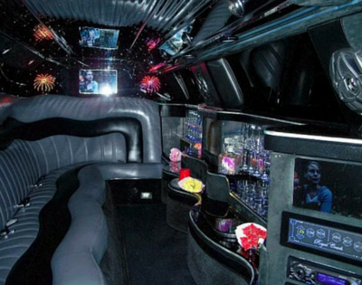 Futuristic black limo interior with curved leather seats, neon lights, and multiple screens