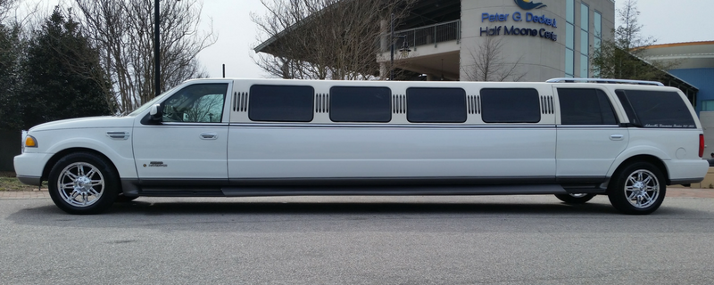 Long white stretch limousine parked beside a building with signs