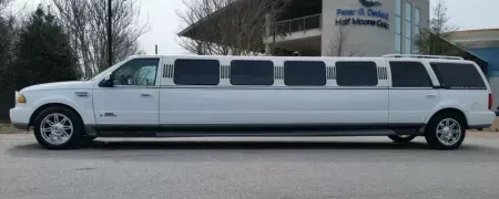 White stretch limousine parked outside a building with a sign in the background