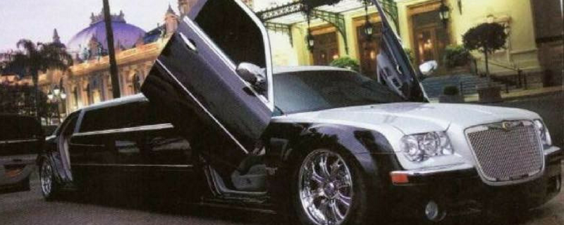Black stretch limousine with scissor door open on a city street at night