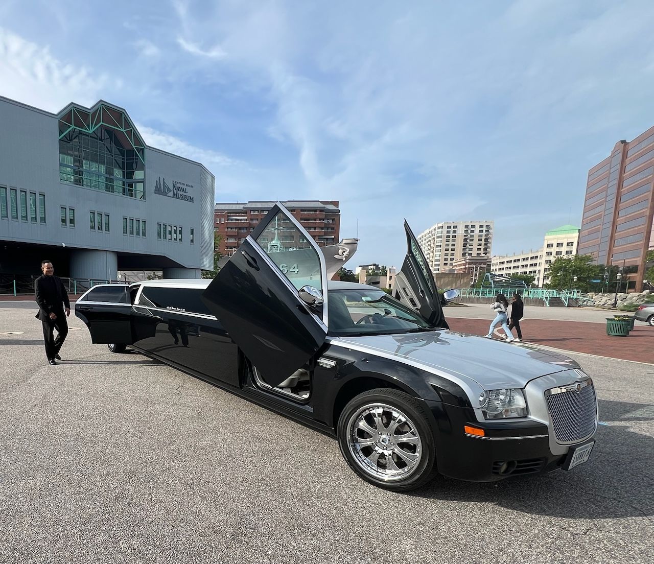Black convertible sports car with gullwing doors open in a city plaza.