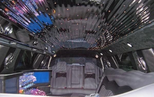Inside a stretched limousine with mirrored ceiling, neon lights, and plush seating