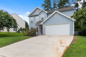 Suburban two-story house with a white garage, red front door, and sloped concrete driveway