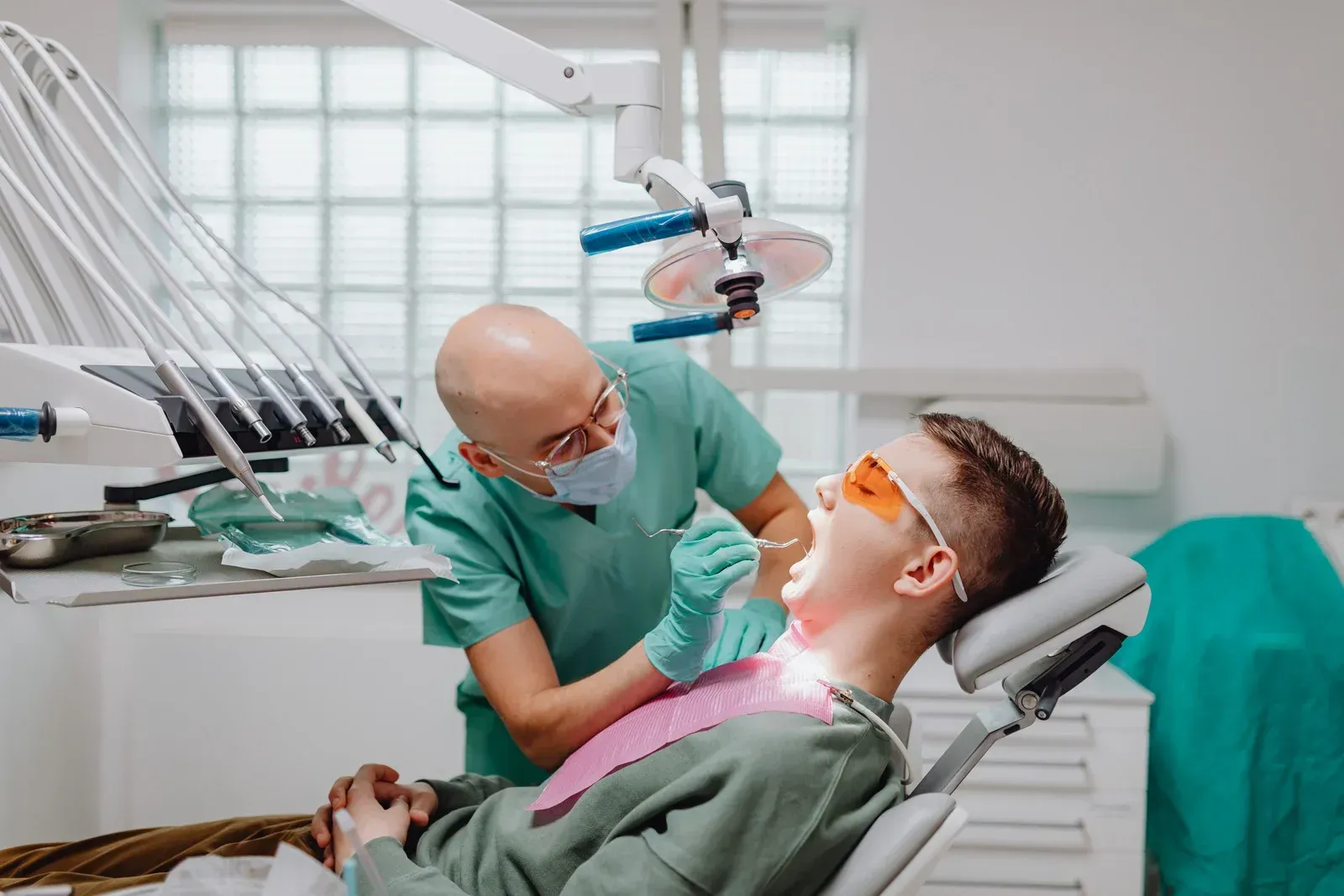 Dentist treating a patient in a bright dental clinic, with tools and overhead light visible