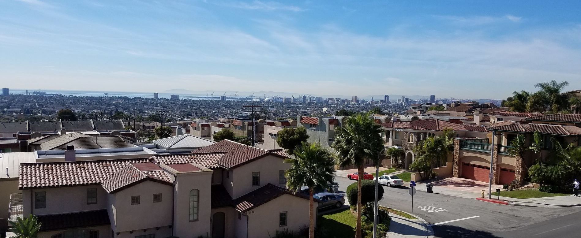 A wide shot of a cityscape and houses under a blue sky.