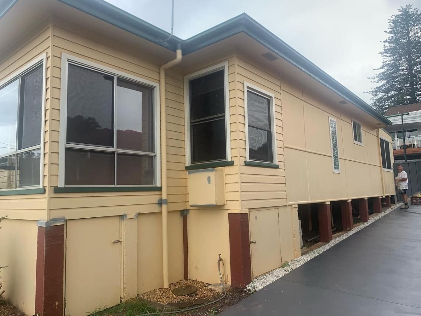 A Yellow House With a Lot of Windows and a Man Standing in Front of It — Holster Painting Contractors In Port Macquarie, NSW 