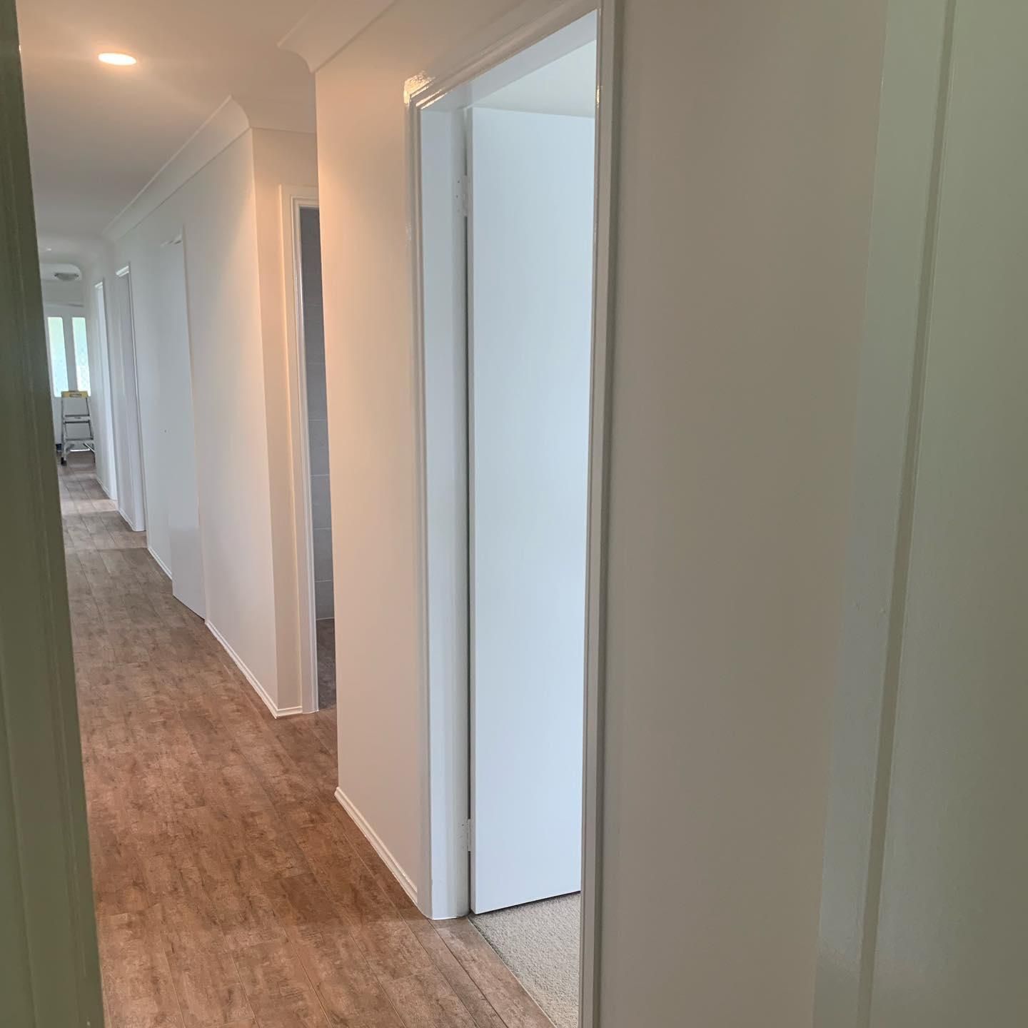 A Long Hallway in a House With Wooden Floors and White Walls — Holster Painting Contractors In Kew, NSW 