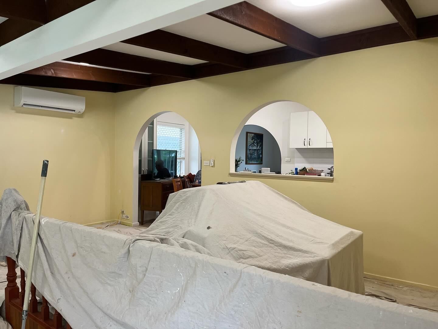 A Room With Yellow Walls and Wooden Beams is Being Painted — Holster Painting Contractors In Port Macquarie, NSW 