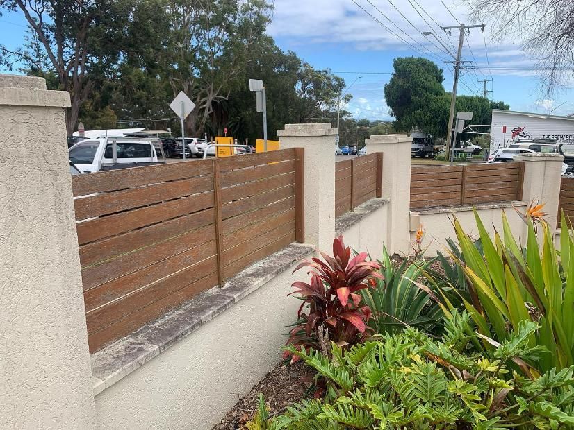 A Wooden Fence is Surrounded by a Lush Green Garden — Holster Painting Contractors In Port Macquarie, NSW
