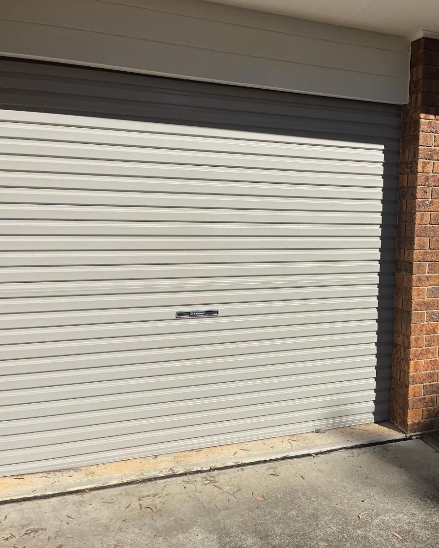 A White Garage Door is Sitting Next to a Brick Wall — Holster Painting Contractors In Port Macquarie, NSW