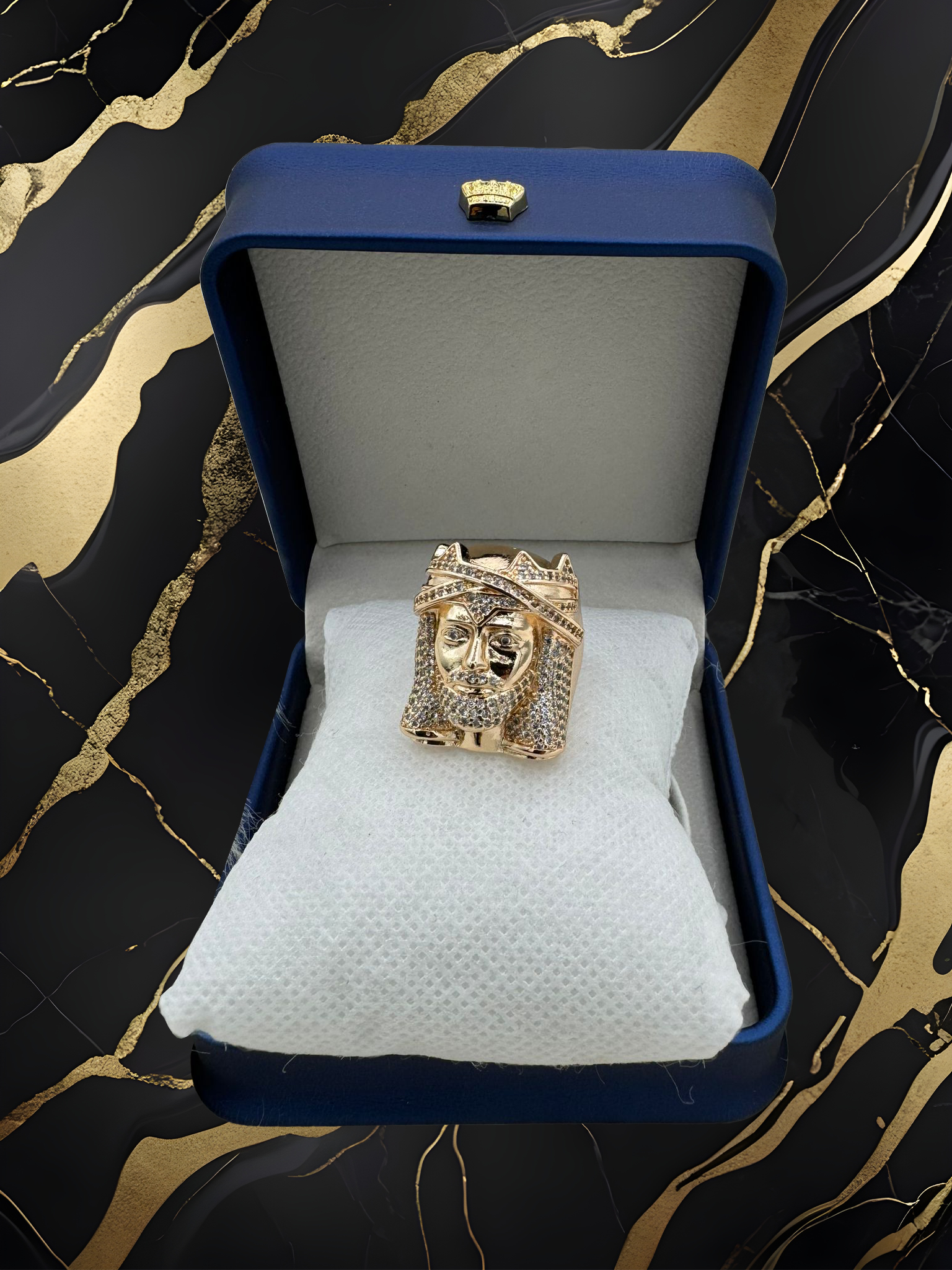 A gold ring is in a blue box on a marble surface.