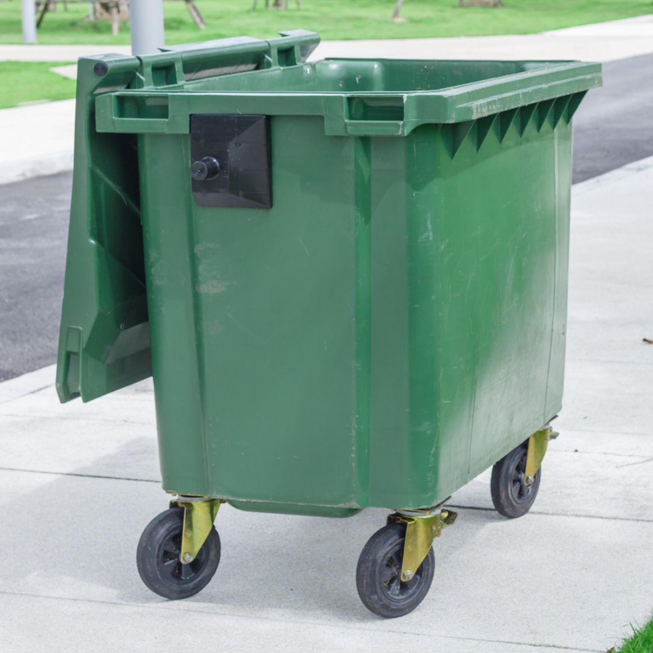 A green trash can with a piece of paper in it.