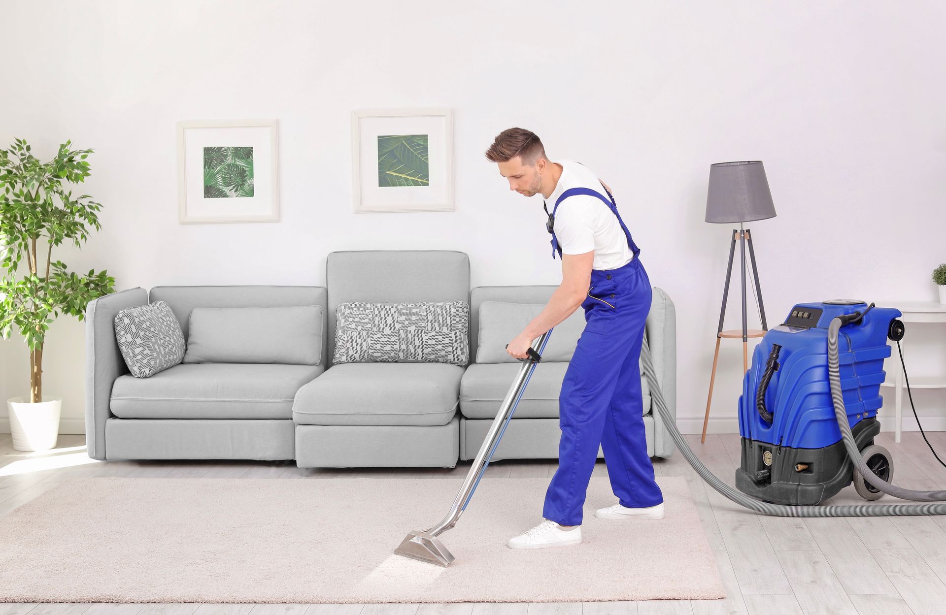A man is cleaning a carpet with a vacuum cleaner in a living room.