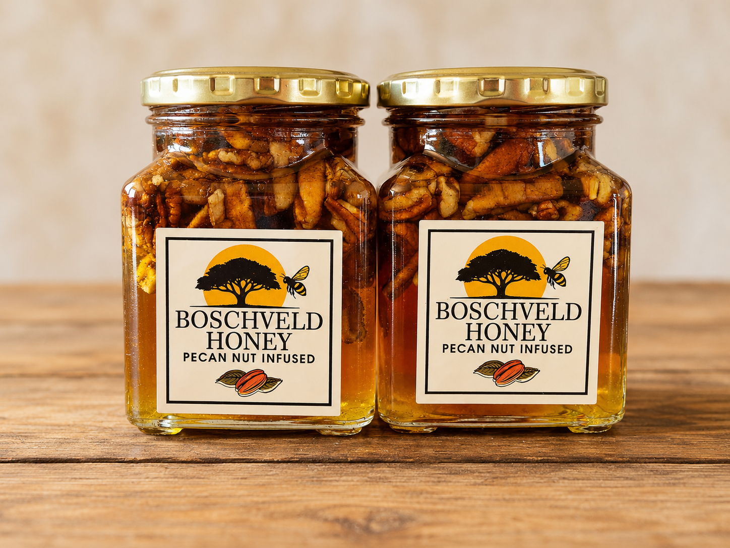 Two jars of Boscheveld honey with gold lids on a wooden table