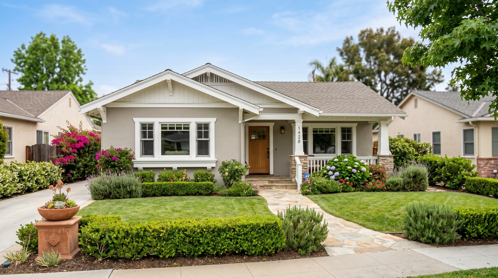 Single-story beige suburban house with white trim, a front porch, and a manicured lawn and shrubs.