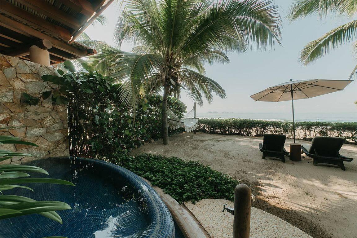 Hay un jacuzzi en la playa junto a una palmera.