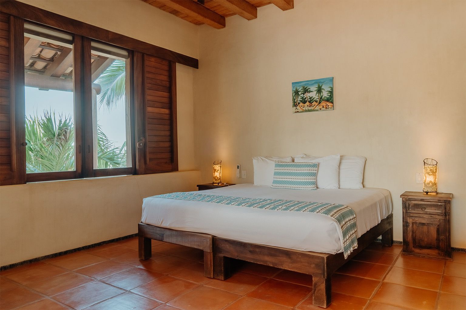 Un dormitorio con una cama, dos mesitas de noche, dos ventanas y un cuadro en la pared.