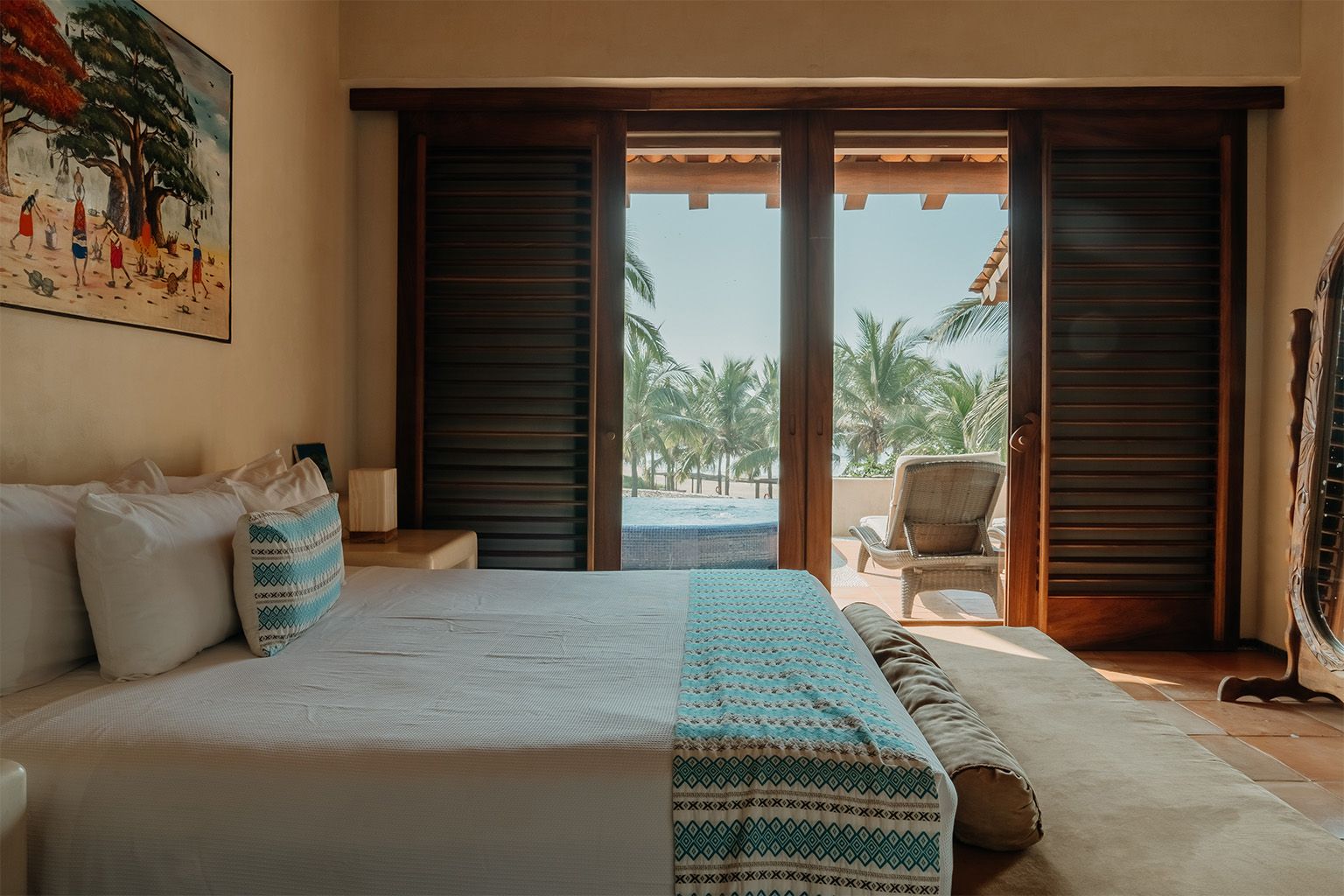 Un dormitorio con una cama tamaño king y puertas corredizas de vidrio que conducen a un patio.