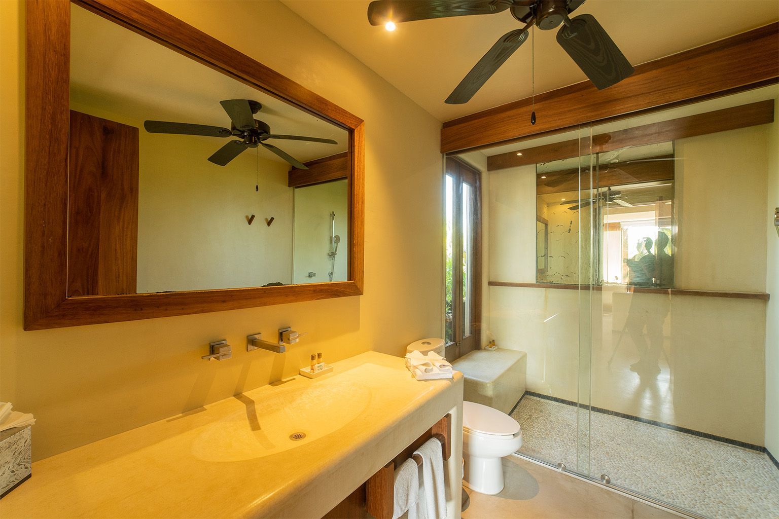 Un baño con lavabo, inodoro, espejo y ventilador de techo.