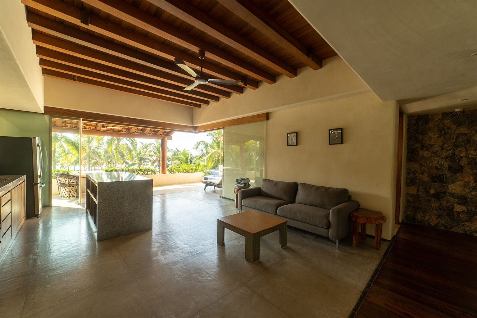 Una sala de estar con sofá, mesa y ventilador de techo.