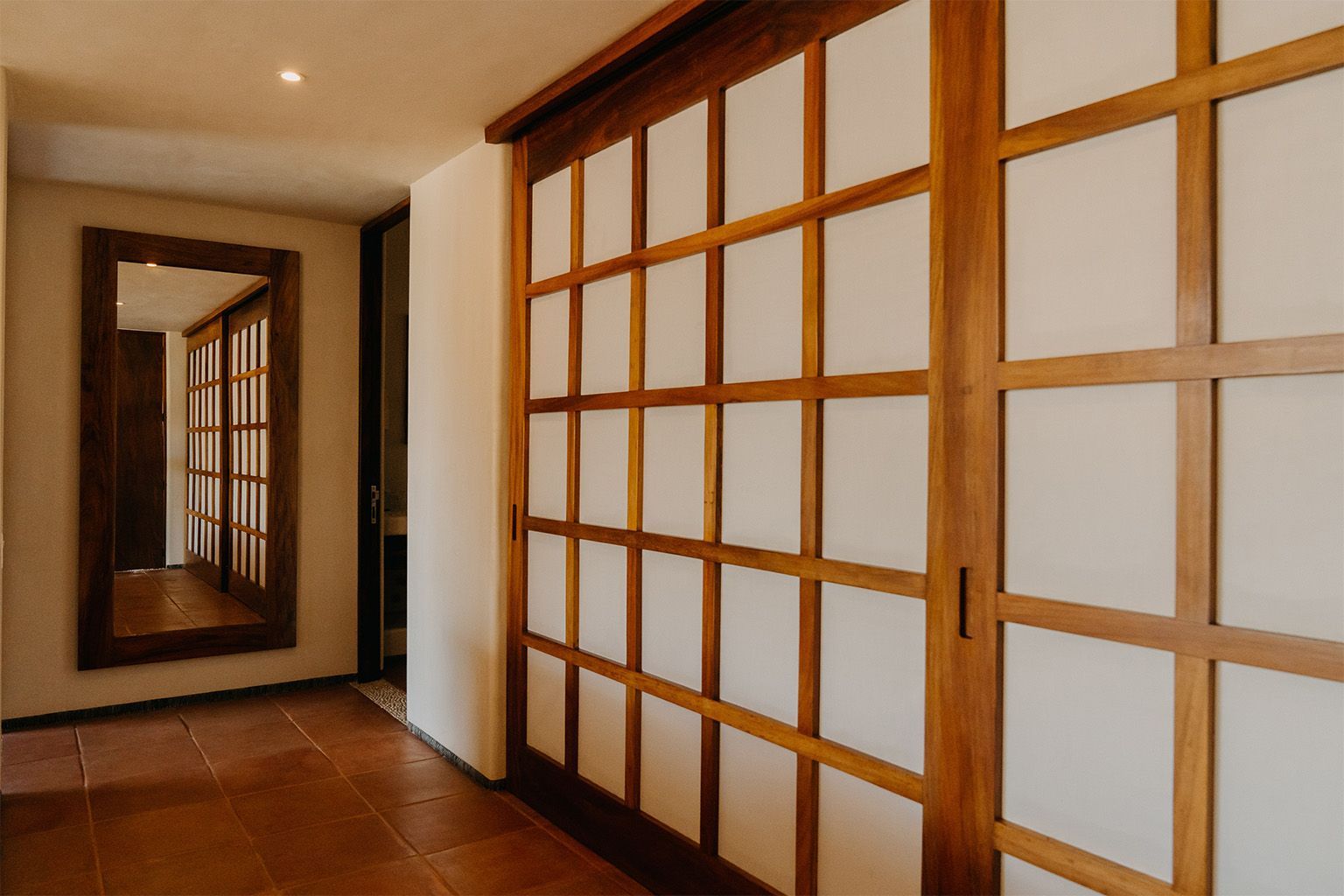 Un pasillo con puertas correderas y un espejo en la pared.