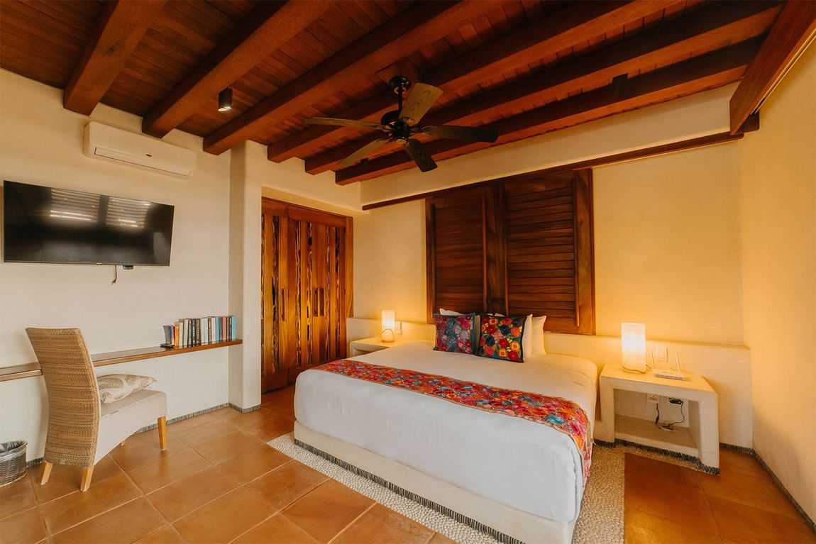 Hay una cama grande en el medio de la habitación con un ventilador de techo.