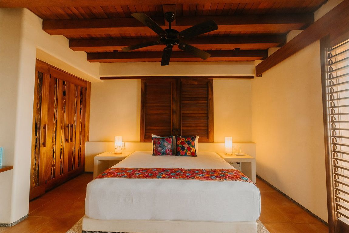 Un dormitorio con una cama king size y un ventilador de techo.