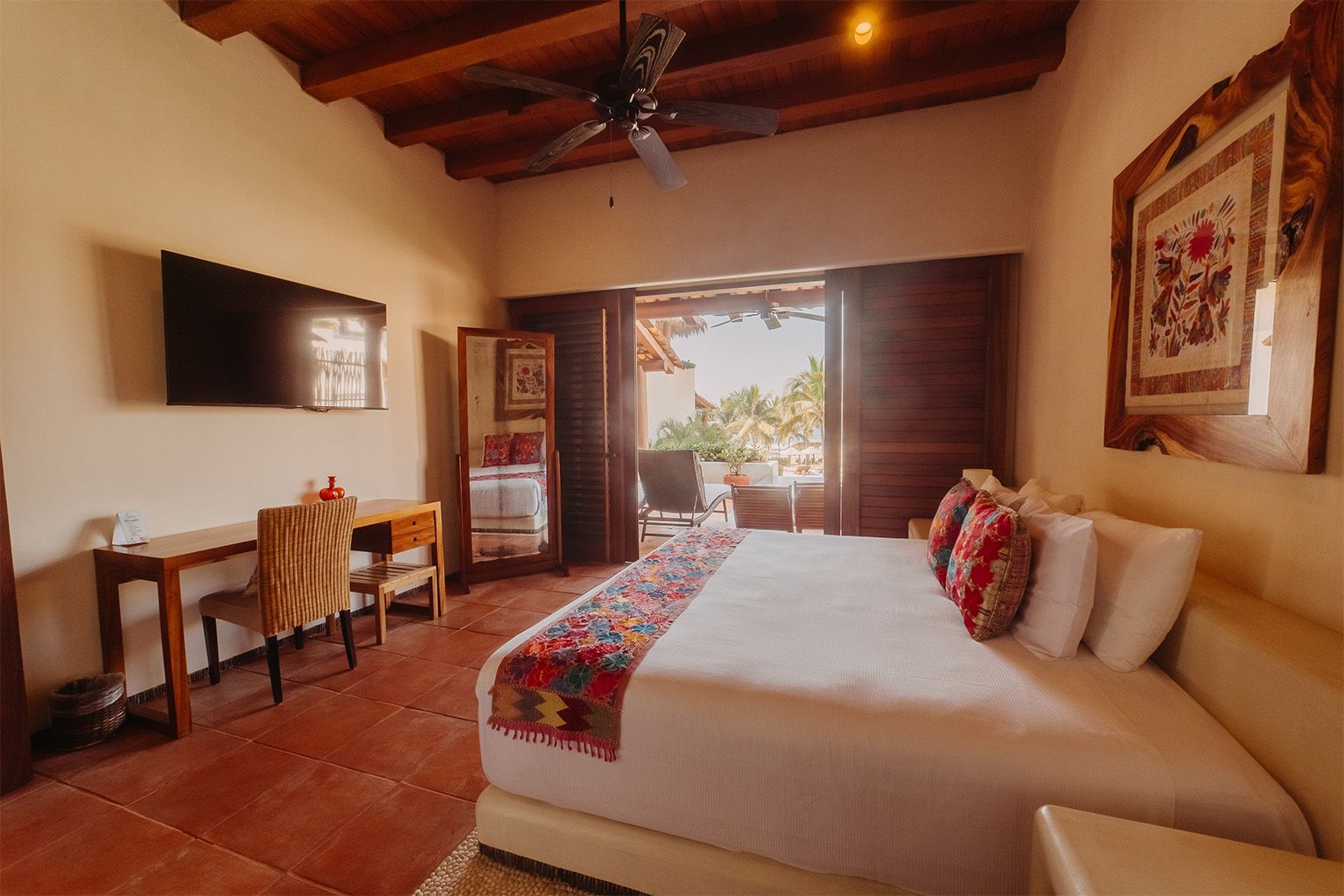 Una habitación de hotel con una cama tamaño king, escritorio, silla y televisión.