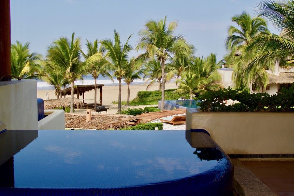 Hay una bañera de hidromasaje en el balcón con vista a la playa y a las palmeras.