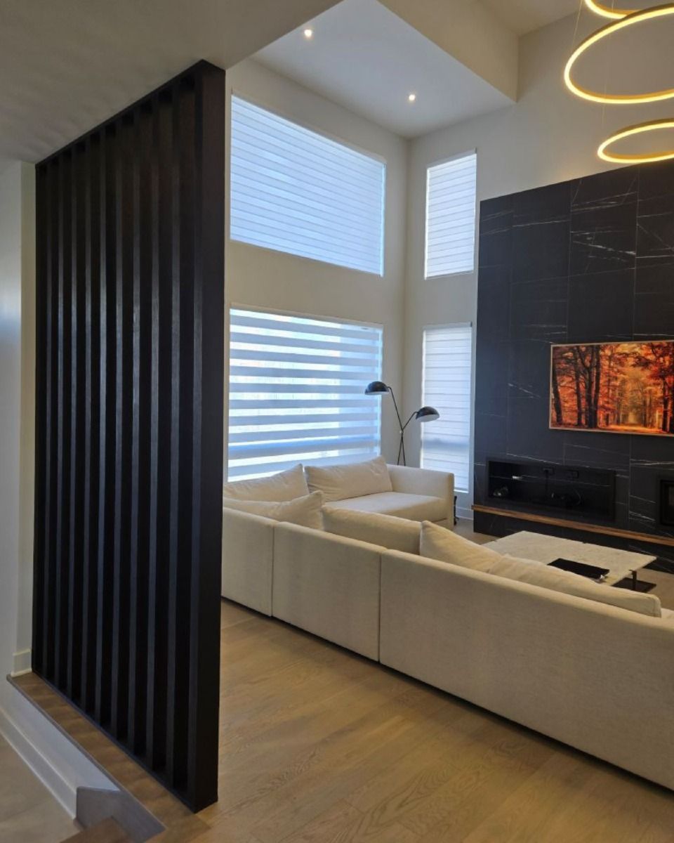 Salon moderne avec mur en lattes de bois foncé, canapé blanc et cheminée en marbre noir.