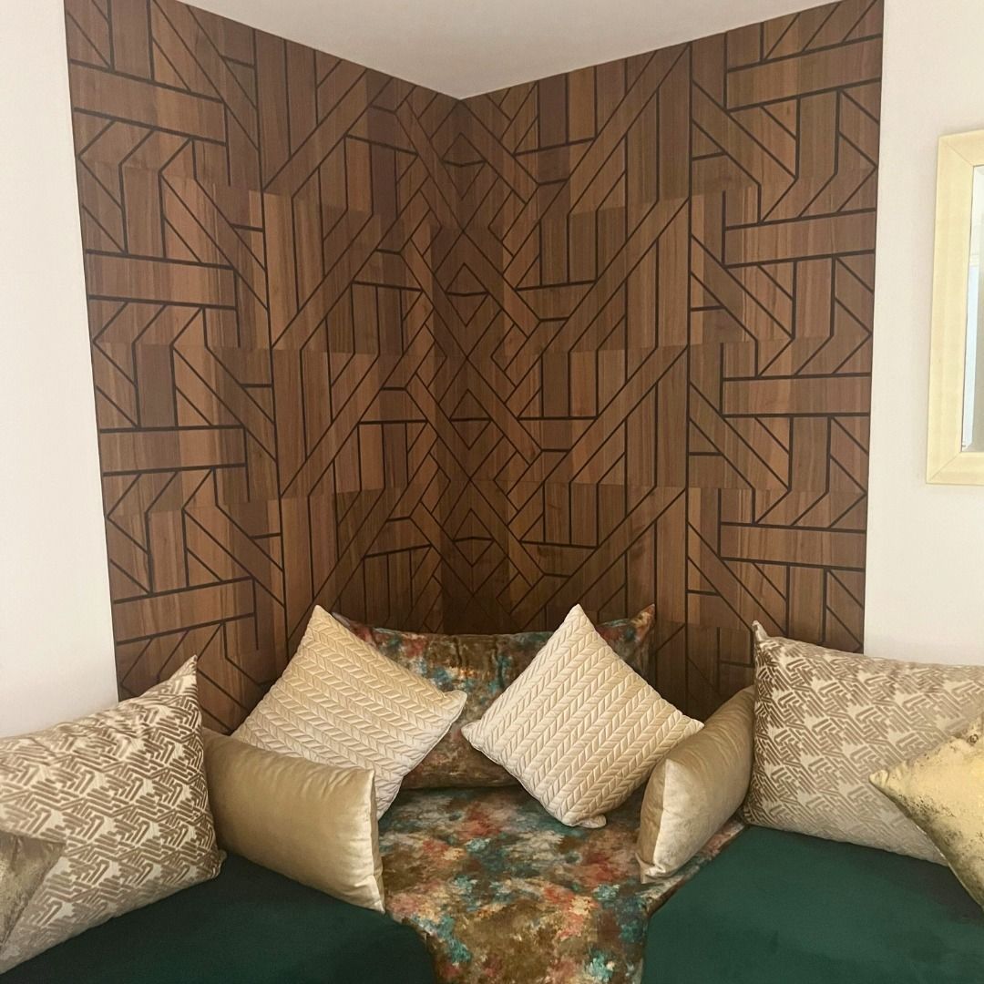 Accent mural géométrique en bois derrière un canapé vert avec des oreillers.