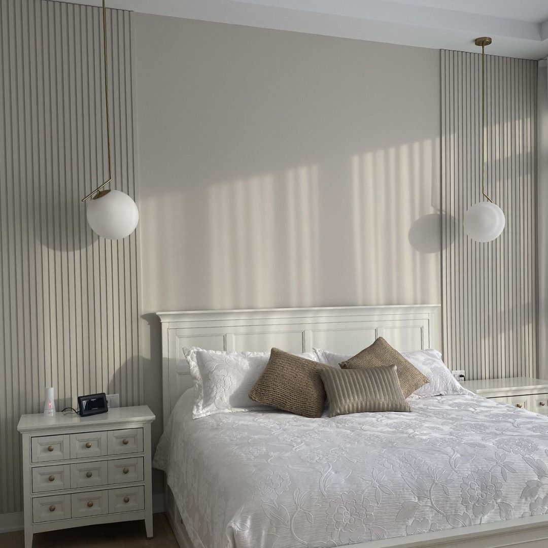 Chambre avec lit, table de chevet, luminaires suspendus et mur texturé.