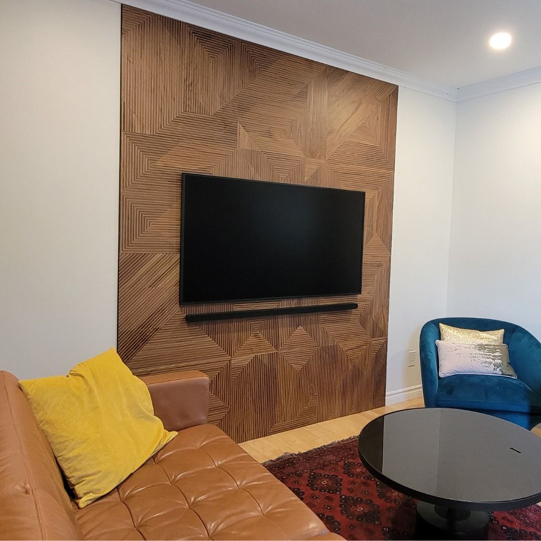 Salon avec canapé en cuir marron, chaise bleue, table basse noire et mur TV en panneaux de bois.