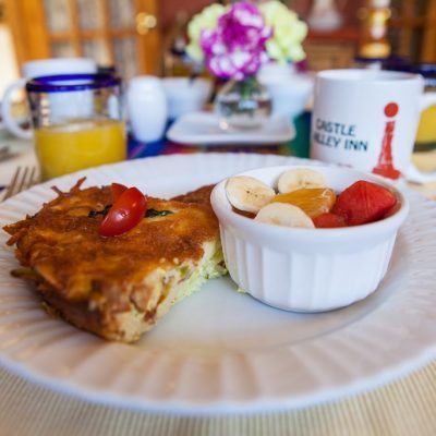 Plate with a slice of toast, fruit cup, and orange juice on a breakfast table