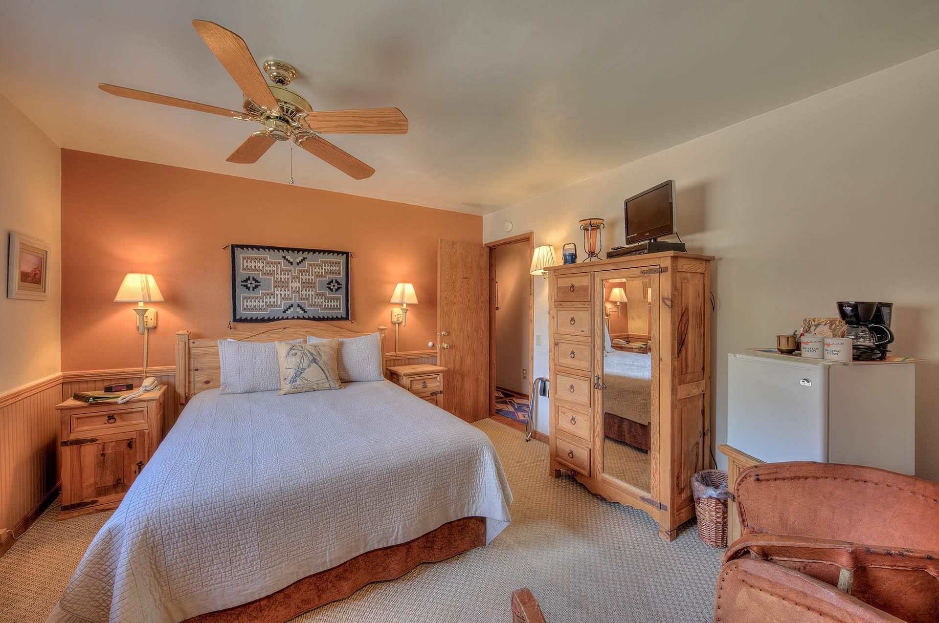 Cozy bedroom with a bed, wooden armoire, orange accent wall, and ceiling fan.