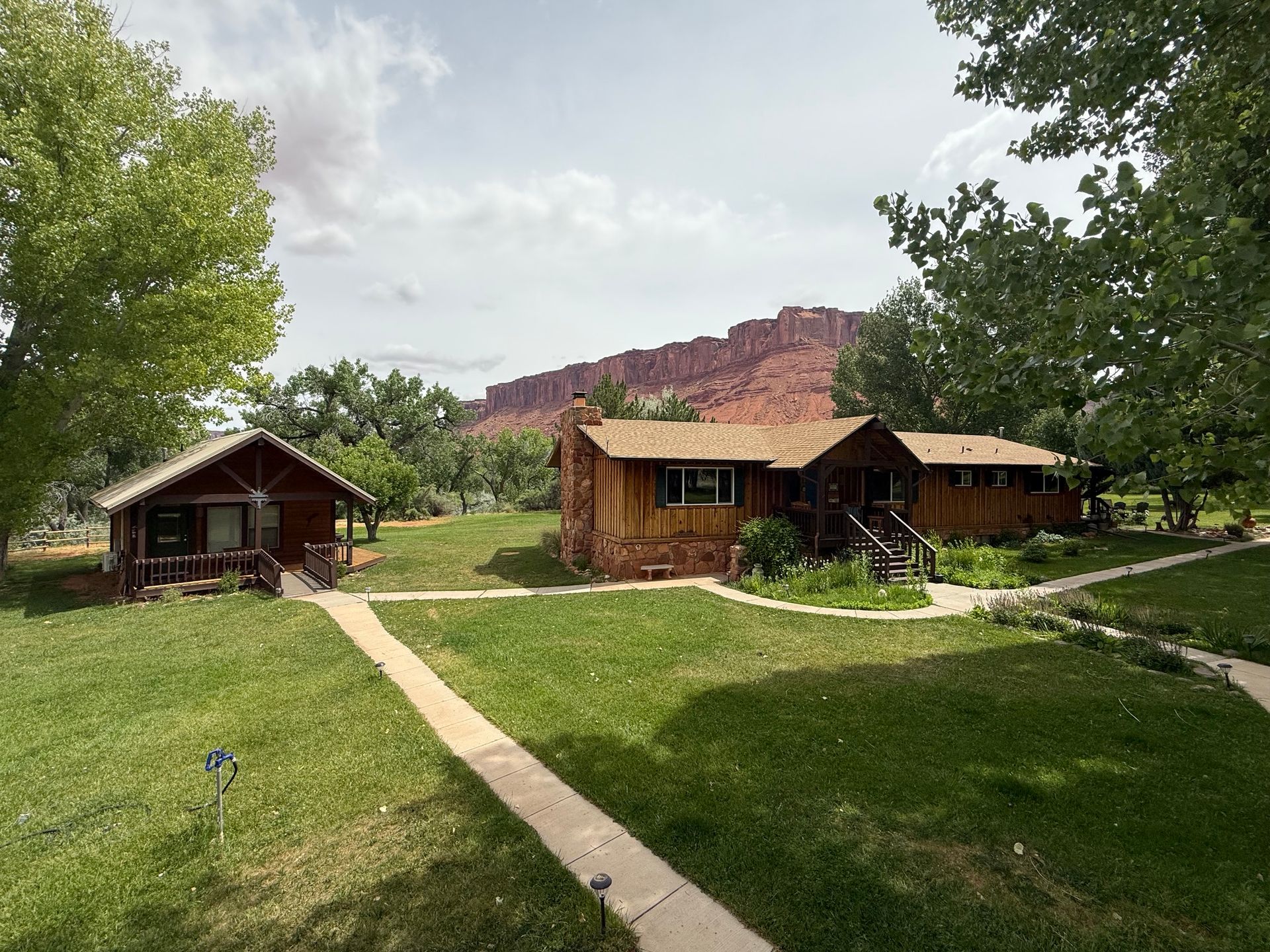 Cabins in a grassy campground with a red rock cliff in the background