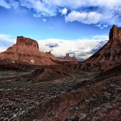 Red rock desert canyon under a bright blue sky with scattered clouds