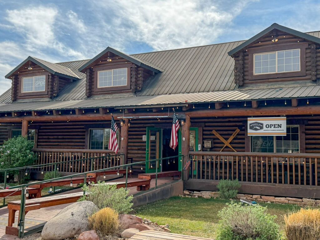 Rustic lodge-style building with porch, American flags, and a sign under a cloudy sky