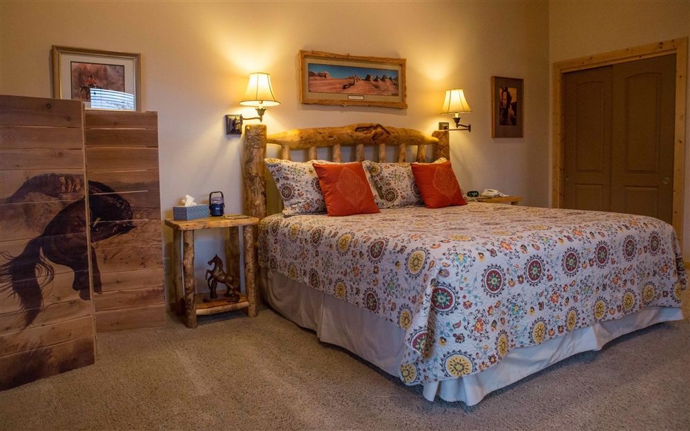 Cozy bedroom with a large bed, warm lamps, framed art, and patterned bedding