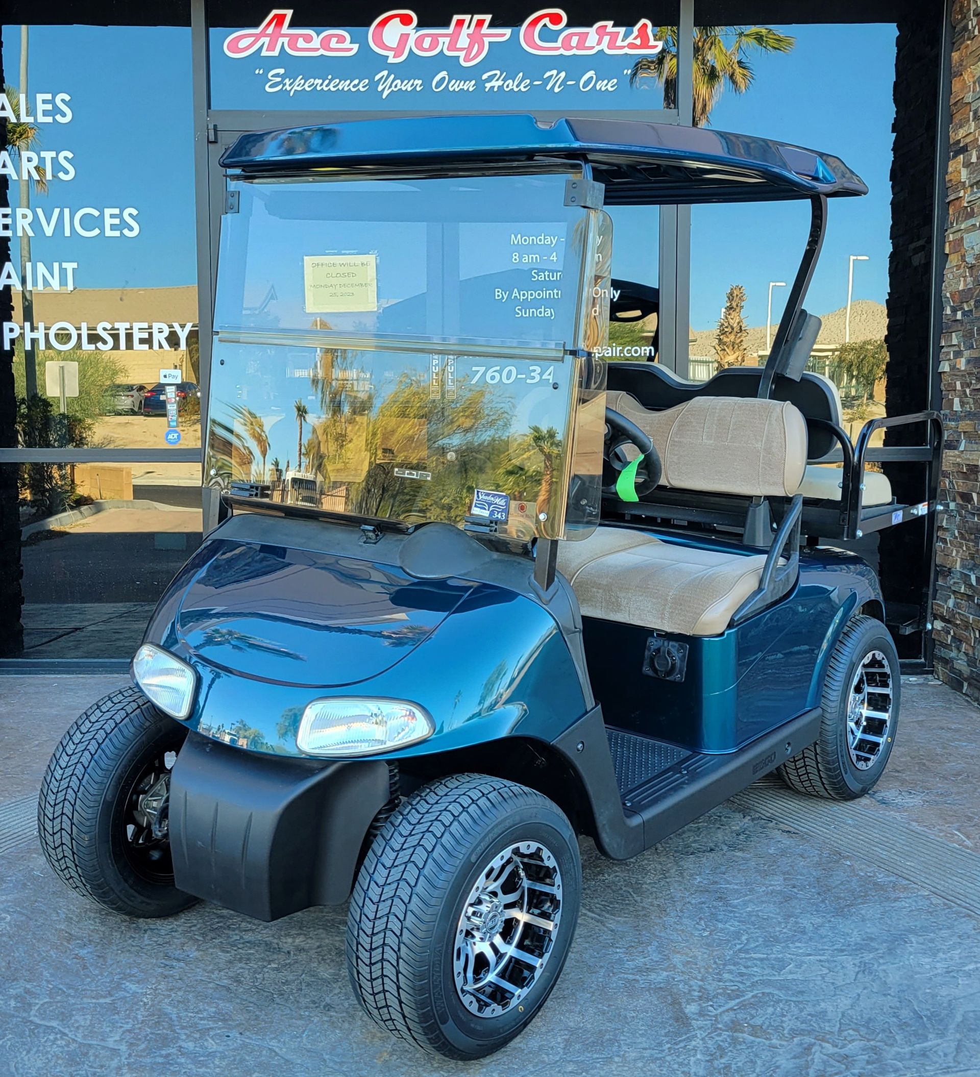 A blue golf cart is parked in front of a store called area golf cars