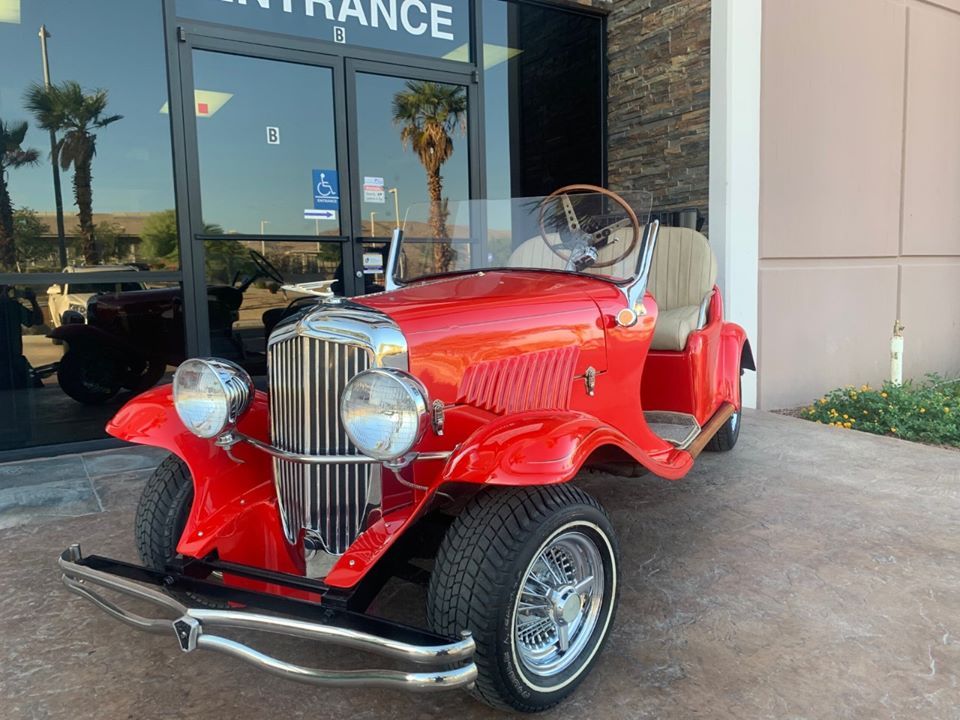 A red golf cart is parked in front of a building.